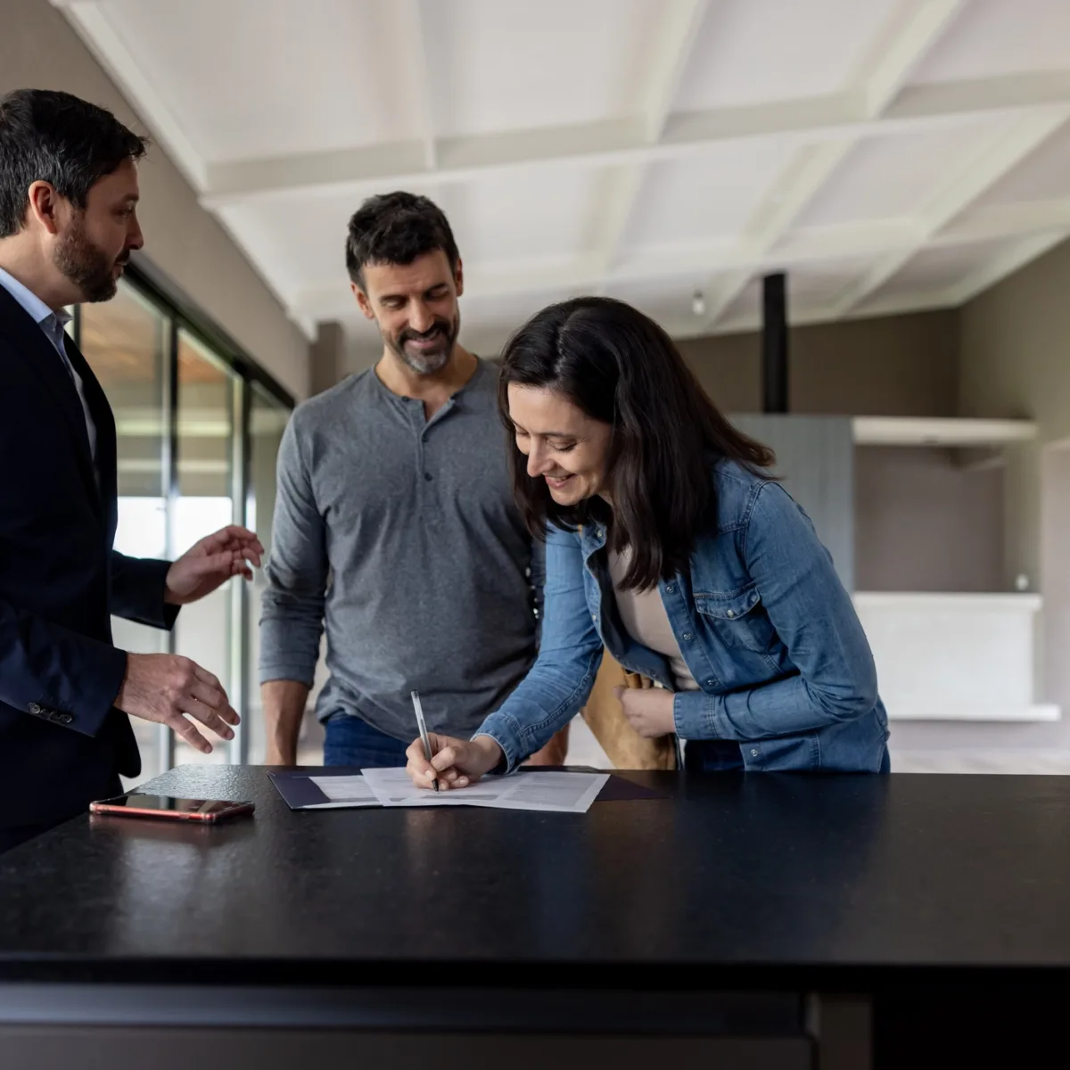 Couple achetant une maison et signant l’acte devant son agent immobilier