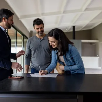 Couple achetant une maison et signant l’acte devant son agent immobilier