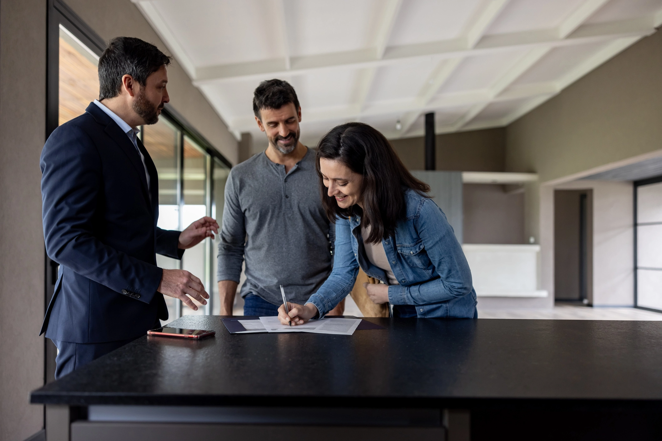 Couple achetant une maison et signant l’acte devant son agent immobilier