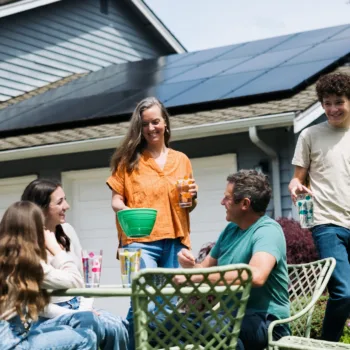 Famille dégustant une collation en plein air devant une maison équipée de panneaux solaires