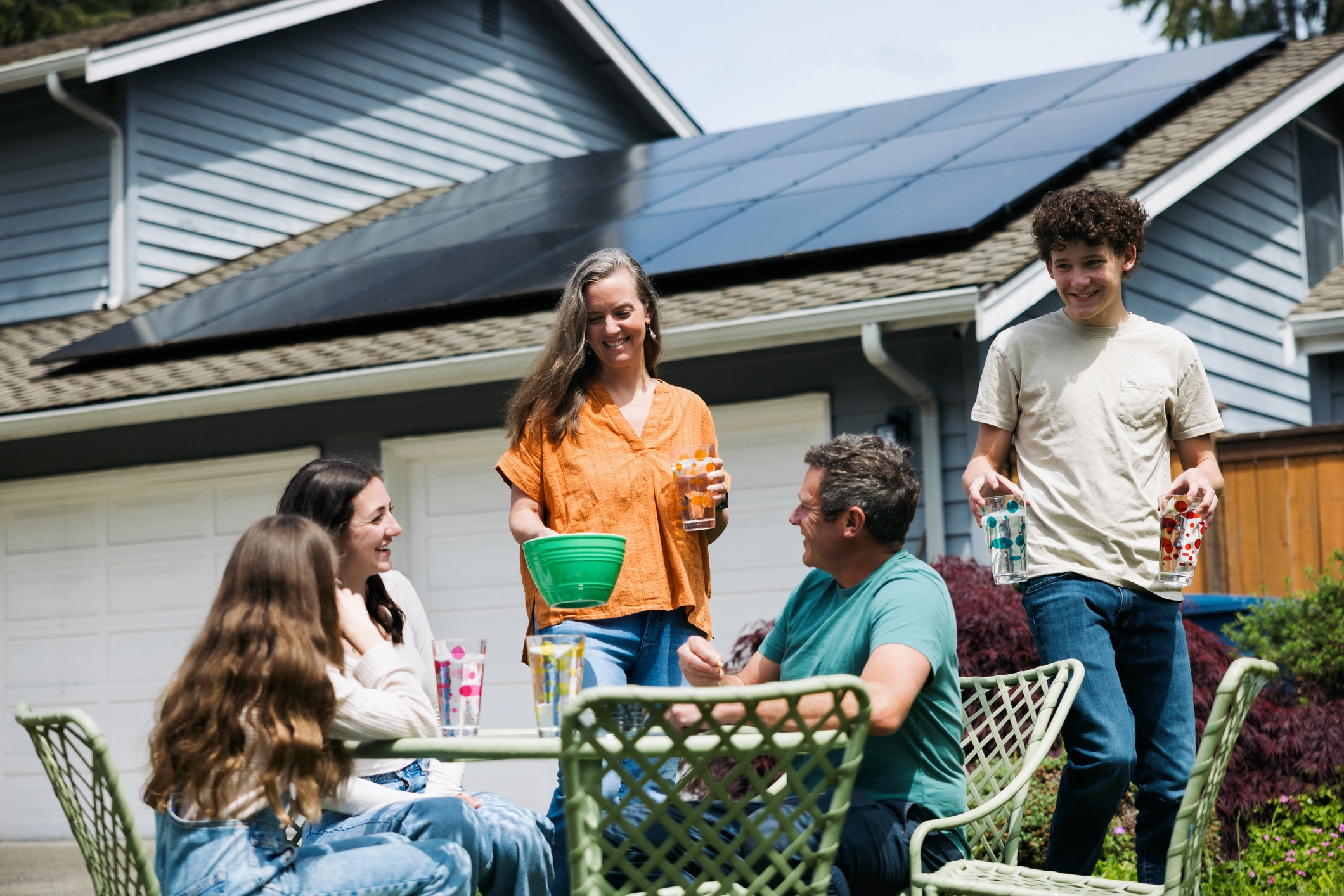 Famille dégustant une collation en plein air devant une maison équipée de panneaux solaires